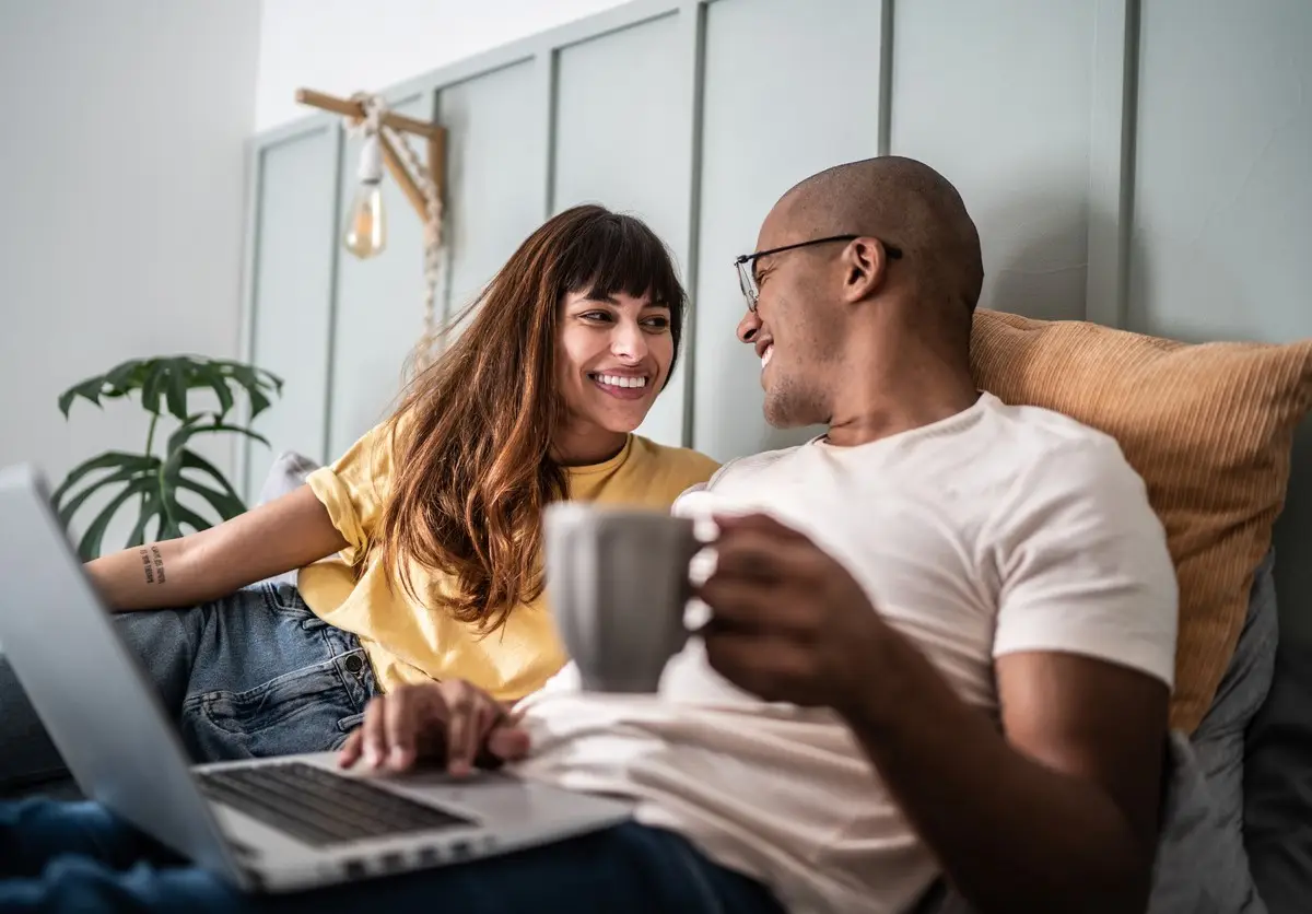 Young couple using the laptop in the bed at home