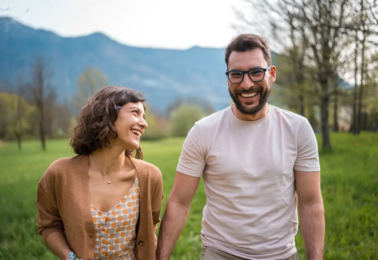 A Hispanic male and Caucasian female enjoy a leisurely walk together, radiating joy in a scenic garden of a boutique hotel, both dressed casually for their intimate outing.