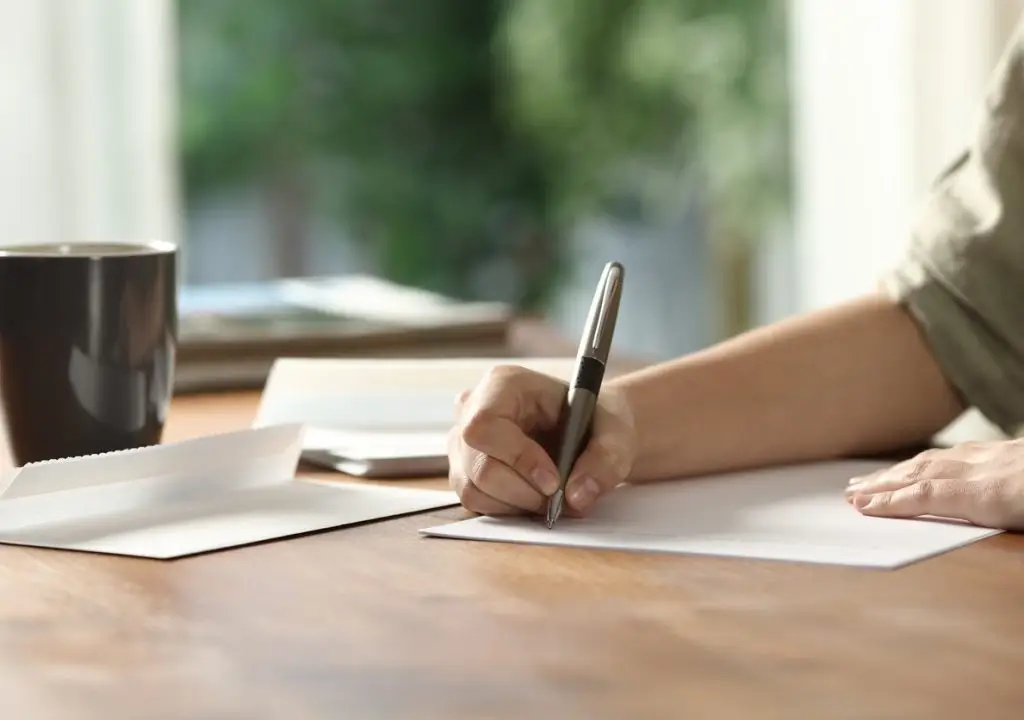 Woman hands handwriting letter on paper at home stock photo